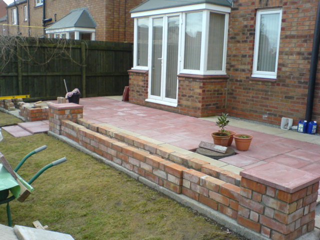 Patio and steps laid, wall almost complete.